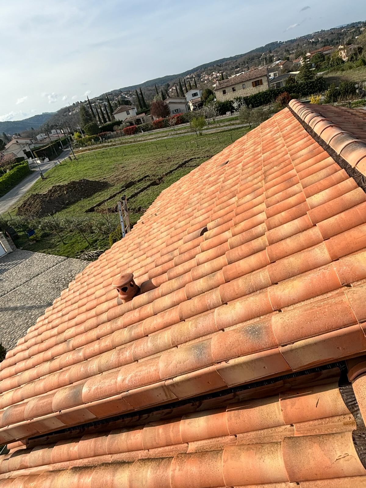 Toiture en tuiles canal fraîchement remise en état, vue sur un quartier résidentiel