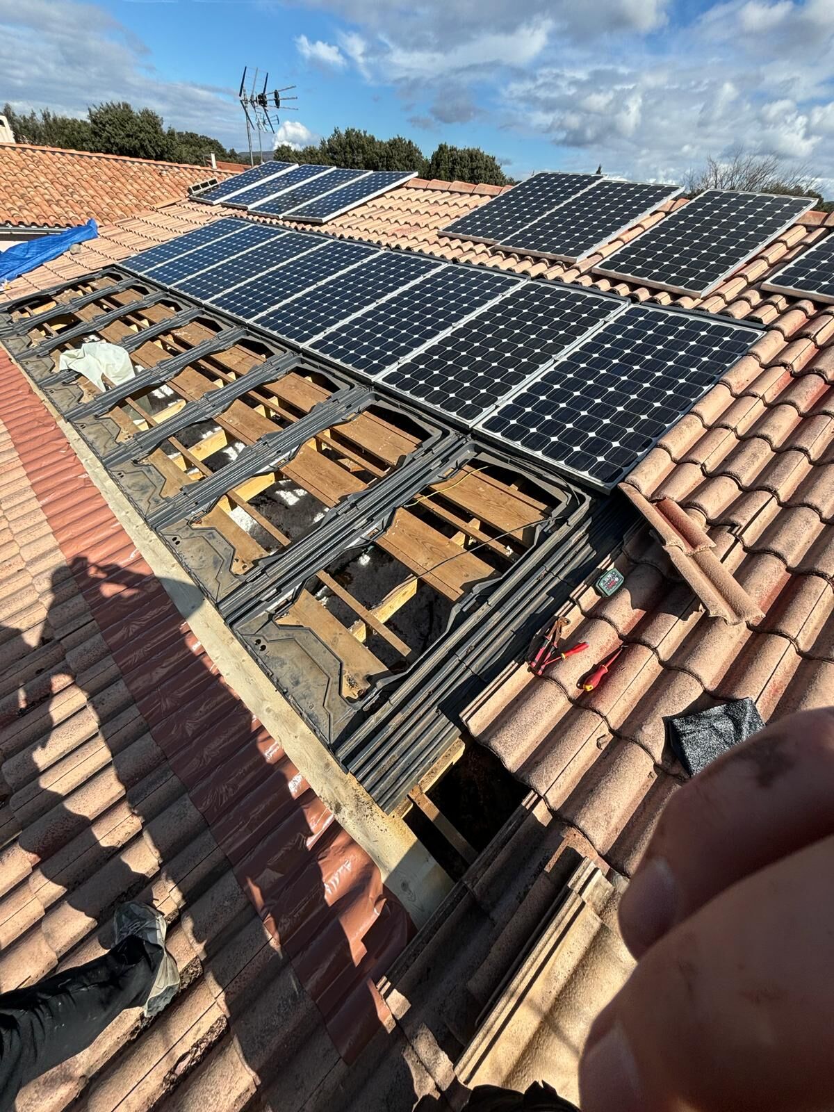 Couverture partiellement déposée autour de panneaux solaires, liteaux apparents